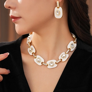 Détail macro de l'ensemble collier et boucles d'oreilles ovales dorés vintage avec émail