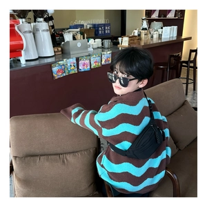 Close-up of a stylish black nylon crossbody chest bag for boys with a trendy knit sweater