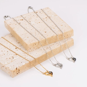 Elegant heart pendant necklaces with zircon crystals on natural stone background