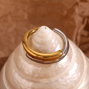 Macro shot of two-tone 18K gold and silver plated crossover ring on white sea shell