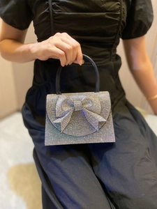 Close-up of a silver rhinestone evening bag featuring a large sparkling crystal bow