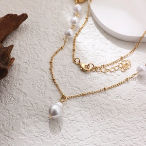 Elegant 14K gold layered necklace featuring round white pearls and gold bead accents