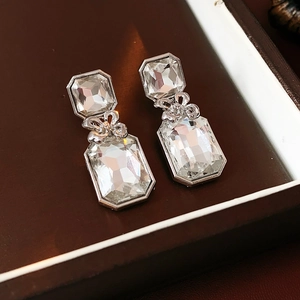 Close-up of silver floral crystal earrings with square stones in a jewelry box