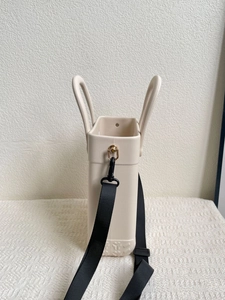 Detail of beige EVA tote bag featuring a metallic D-ring and black nylon shoulder strap