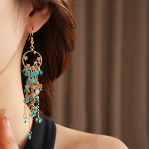 Detail of vintage gold tassel earrings with colorful crystals worn by a model