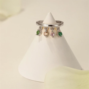 Detailed shot of a silver ring with four colorful gemstone pendants on a white display