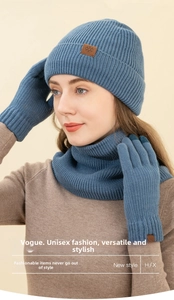 Close-up of grey-blue knit hat, scarf and touchscreen gloves with snowflake patches