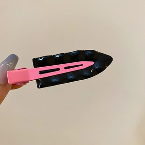 Detail view of the pink duckbill hair clip with wavy black decorative borders and glossy finish