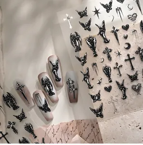 Macro detail of 3D gothic nail stickers featuring black angels and cross patterns