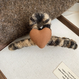 Détail d'une pince à cheveux en peluche léopard avec cœur sur tissu en laine