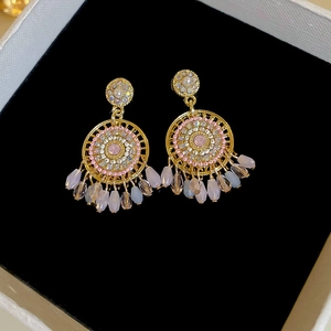 Close-up of bohemian gold hoop earrings with colorful gemstones and pearl tassels
