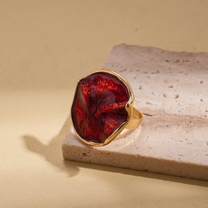 Detailed close-up of dark red enamel cocktail ring on a natural stone base