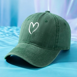 Detailed macro view of heart print on washed dark green cotton twill baseball cap