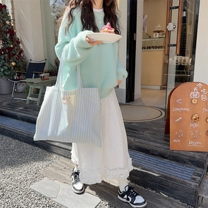 Detailed close-up of light blue and white vertical striped canvas tote bag with logo tag