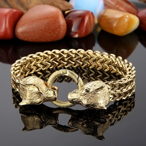 Macro detail of gold viking wolf head bracelet with heavy link chain on mineral stones