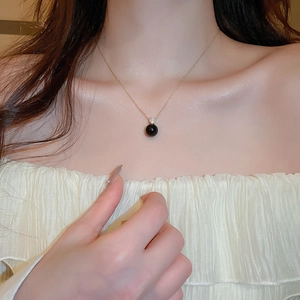 Elegant gold necklace featuring a minimalist black pearl pendant and zircon stone on a model