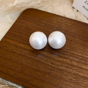Dettaglio degli orecchini di perle con trama setosa su espositore in legno