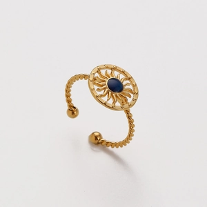 Macro detail of gold-plated sun-shaped ring with twisted band and blue gemstone inlay