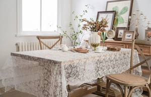 Detailed view of white floral embroidery and scalloped edges on a lace tablecloth