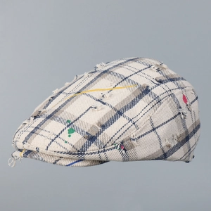 Close-up of distressed plaid flat cap with vintage paint splatter and frayed details