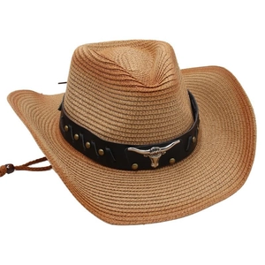 Detail of western straw cowboy hat featuring black leather band and silver bull head emblem