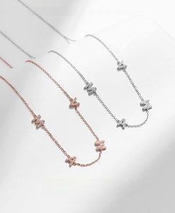 Detailed close-up of MAMA letter necklaces in rose gold and silver with sparkling crystals