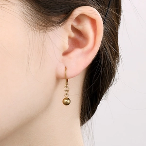 Detailed close-up of polished gold bead drop earrings on model with high gloss finish
