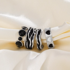 Set of four silver stainless steel rings with black and white enamel geometric patterns