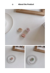 Detail of mini shell-shaped hair clips in cream, pink, and green with golden stripes