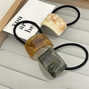 Close-up of minimalist resin hair ties set in marble white, amber, and ink black patterns