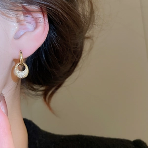 Detailed close-up of gold oval hoop earrings with a textured hammered metal surface