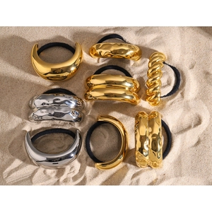 Detail of assorted gold and silver metallic elastic hair ties on a sandy background