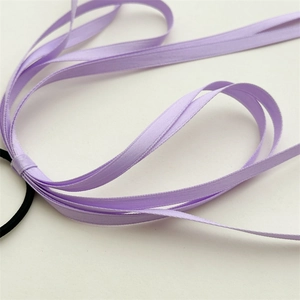 Close-up of purple layered silk ribbons with high-elastic black hair tie on white background