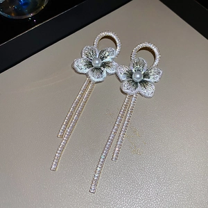 Détail macro de boucles d'oreilles fleurs en tulle avec perles et franges scintillantes