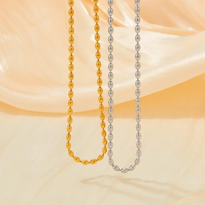 Irregular stainless steel gold and silver beaded necklace on yellow velvet background