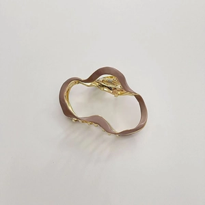 Detail of a wavy metal hair claw clip with gold frame and premium morandi enamel finish