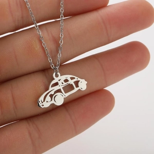 Macro detail of silver stainless steel vintage car pendant necklace held in hand