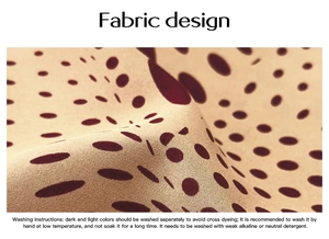 Detail der Stofftextur des beige Oberteils mit roten Punkten und Waschanleitung