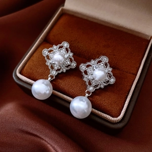 Detailed close-up of vintage hollow rhombic earrings with pearls and zircon stones