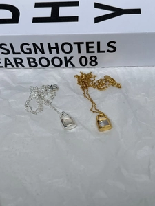 Detail view of gold and silver key lock pendants with white mother of pearl inlay