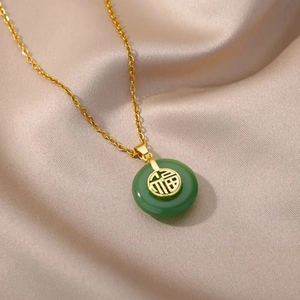 Detail of clover necklace with gold Fu character on green pendant and silk texture