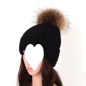 Detailed close-up of thick black winter knit beanie featuring a large brown faux fur pompom