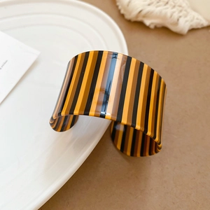 Macro shot of vertical striped acrylic cuff bracelet featuring retro brown and black tones