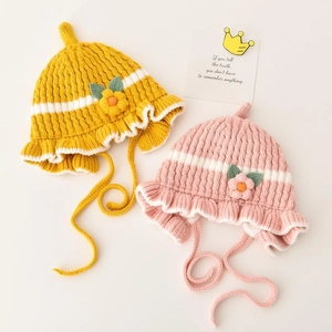 Two adorable knit baby hats in yellow and pink with floral accents and tie chin straps