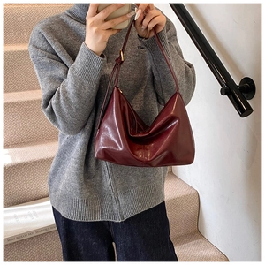 Close-up of wine red glossy patent leather shoulder bag with gold adjustable buckle