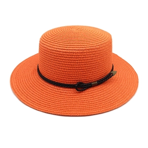 Close-up of orange straw sun hat with black woven band and antique bronze arrow buckle