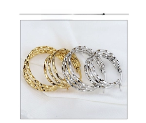 Detailed view of intertwined triple-layer twisted rope earrings in gold and silver steel