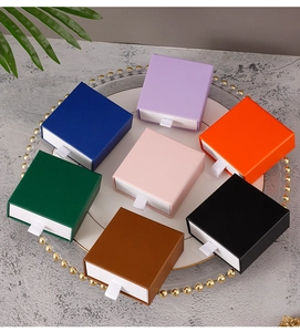 Square drawer-style jewelry gift boxes in seven vibrant colors displayed on a white plate