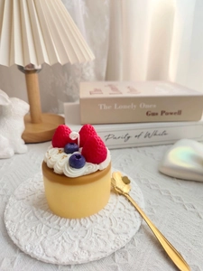 Detailed view of a handmade strawberry cake scented candle on a white lace coaster