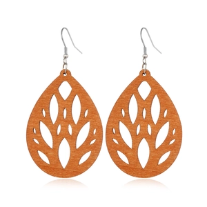 Detailed close-up of brown wooden teardrop earrings with intricate hollow leaf design